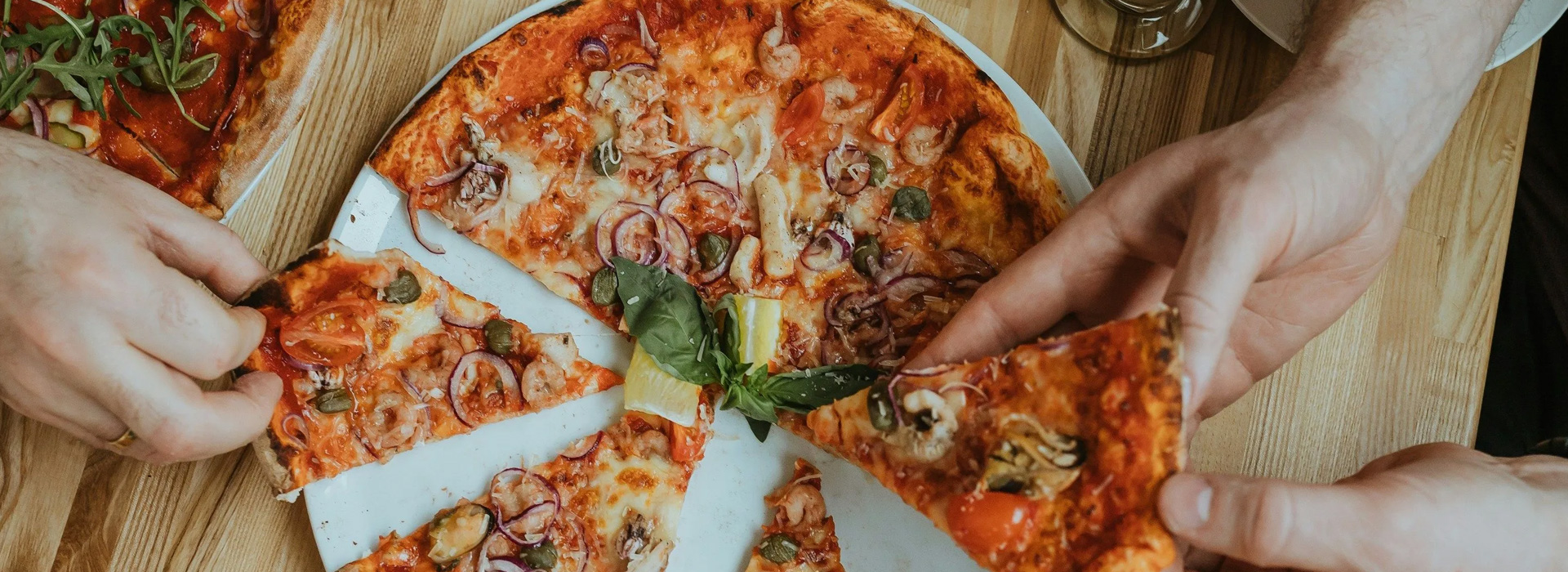 personas compartiendo pizza en pizzería