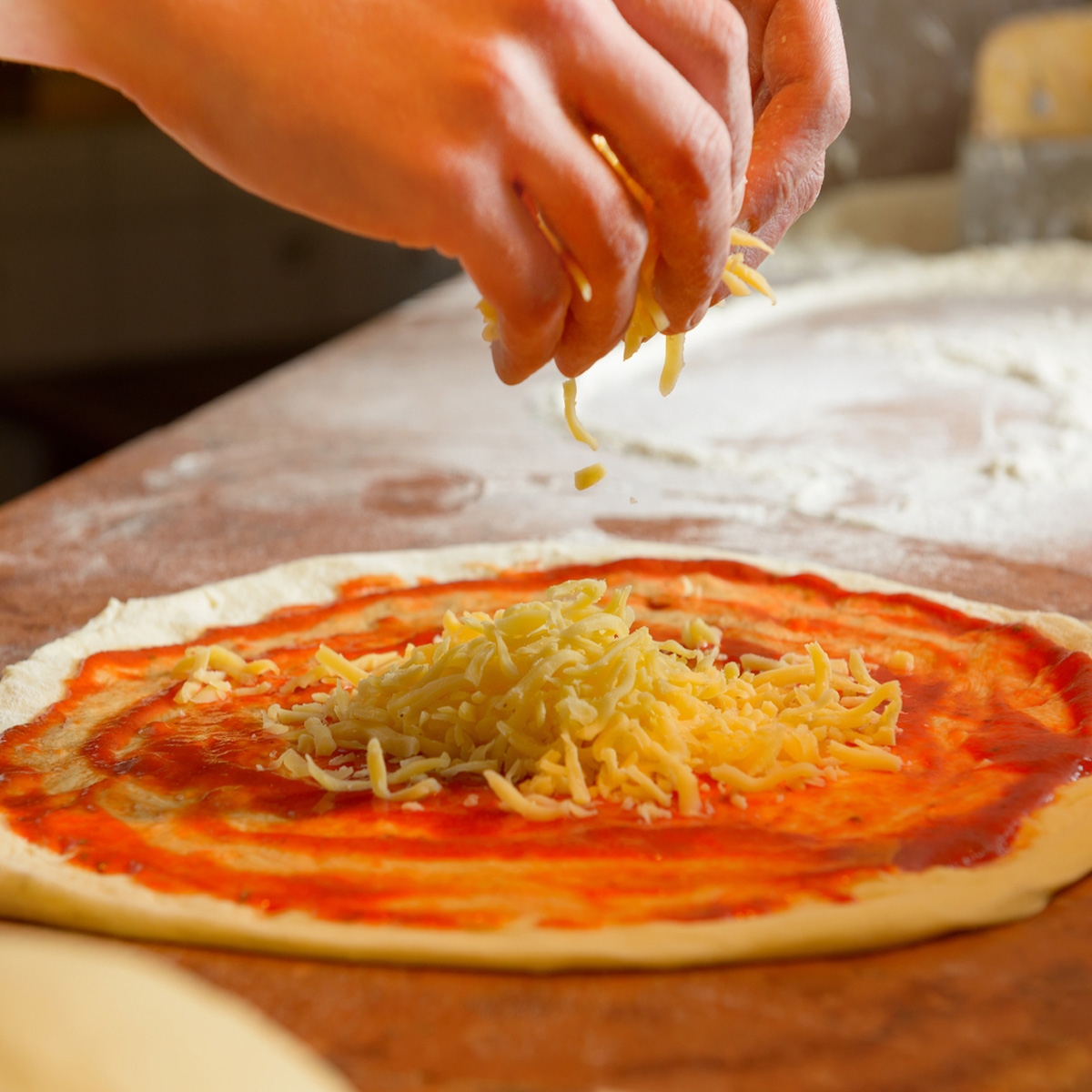 preparación de pizza artesanal mozzarella sobre tomate y masa casera